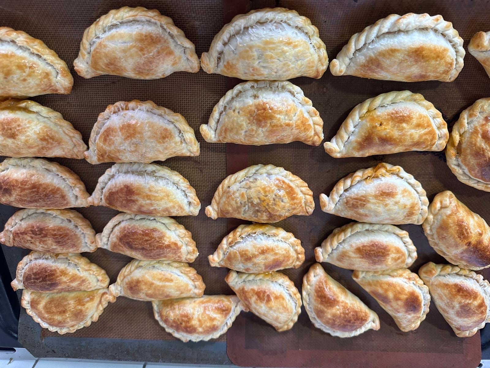 A baking sheet of empanadas, wide view